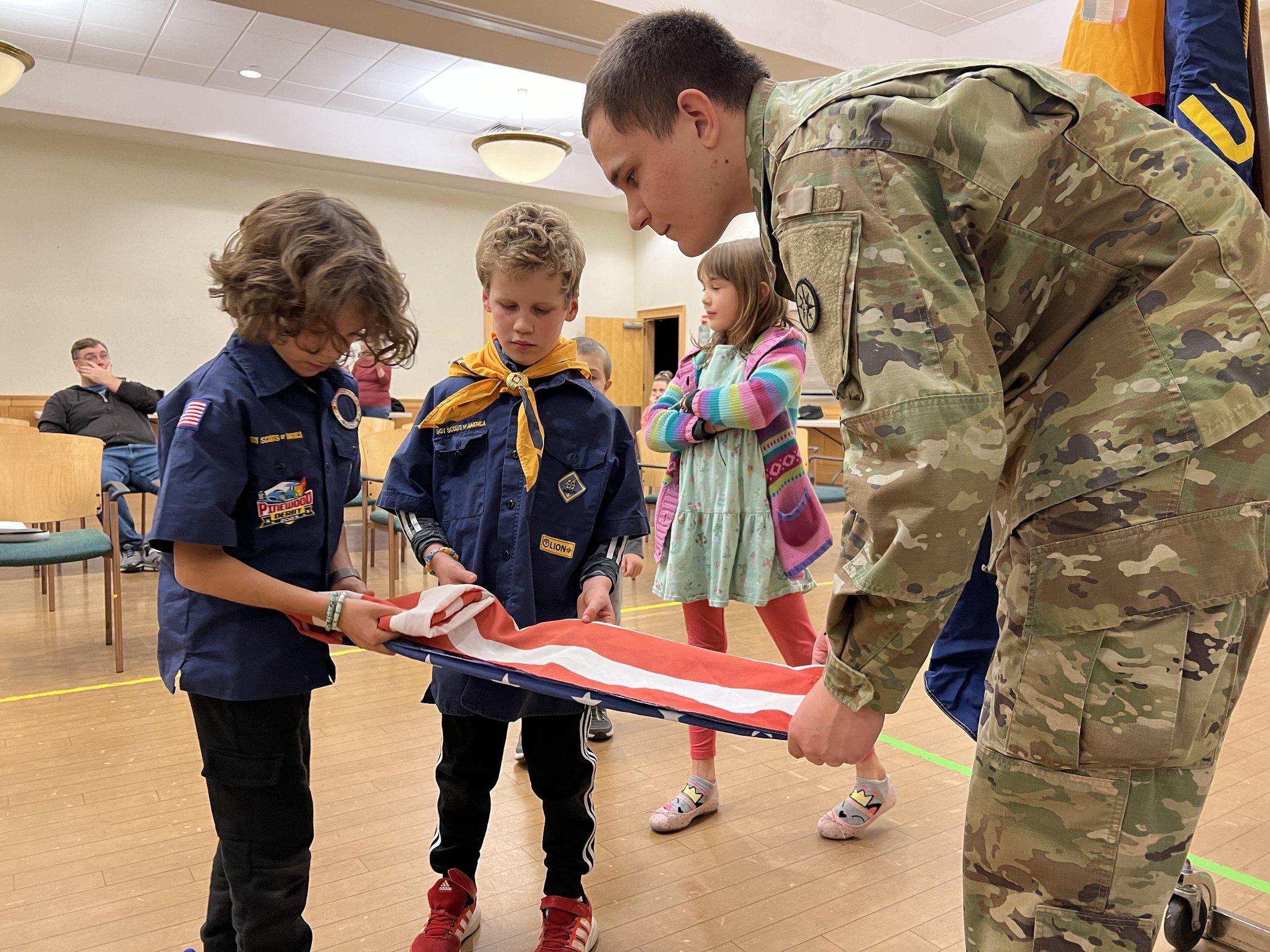 Scouts learning flag folding from a soldier