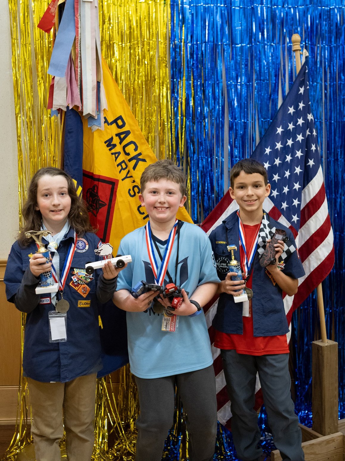 Scouts holding Pinewood Derby trophies